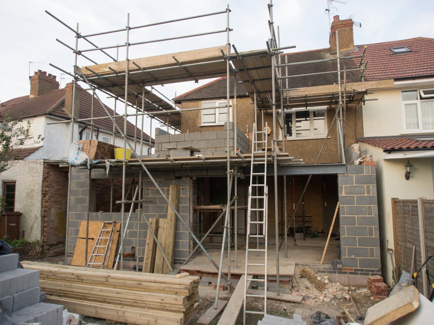 Casa in costruzione con ponteggi e materiali edili.