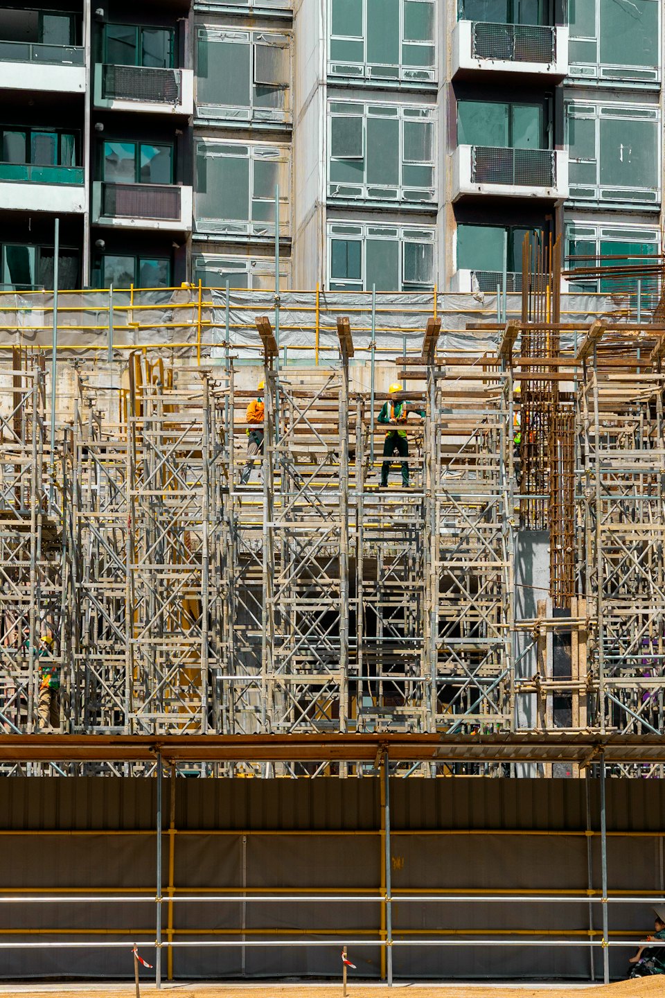 Operai edili con giubbotti di sicurezza costruiscono un cantiere pluripiano.