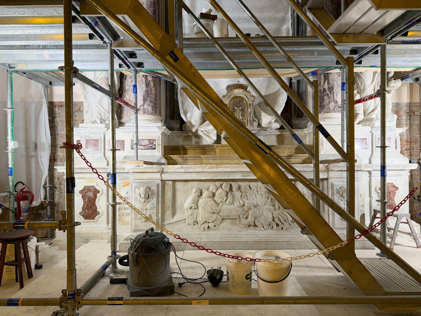Impalcature e attrezzature circondano un monumento in pietra sottoposto a lavori di restauro.